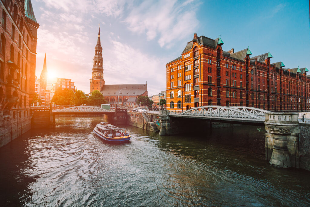 Touristic cruise boat on a channel with bridges in the old warehouse district Speicherstadt in Hamburg in golden hour sunset light